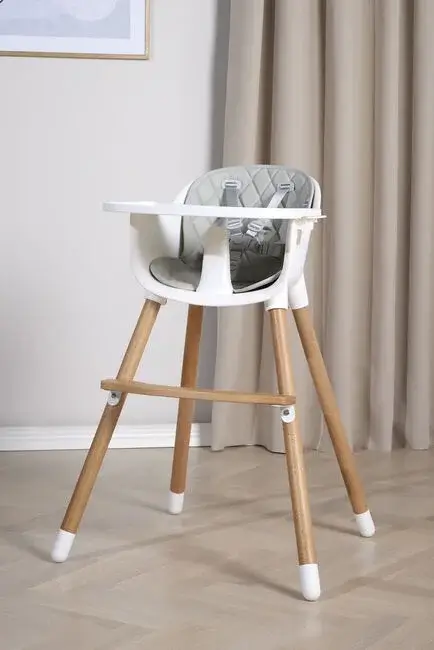Valkoinen vauvan syöttötuoli puujaloilla ja tarjottimella sisustetussa olohuoneessa