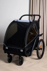 Musta lasten kuljetuskärry kolmella pyörällä sisätiloissa