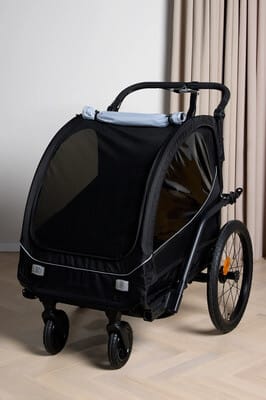 Musta lasten kuljetuskärry kolmella pyörällä sisätiloissa