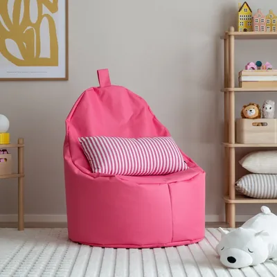 Kirkkaan pinkki säkkituoli lastenhuoneessa, jossa on raidallinen tyyny, leluhylly ja pehmeä matto.